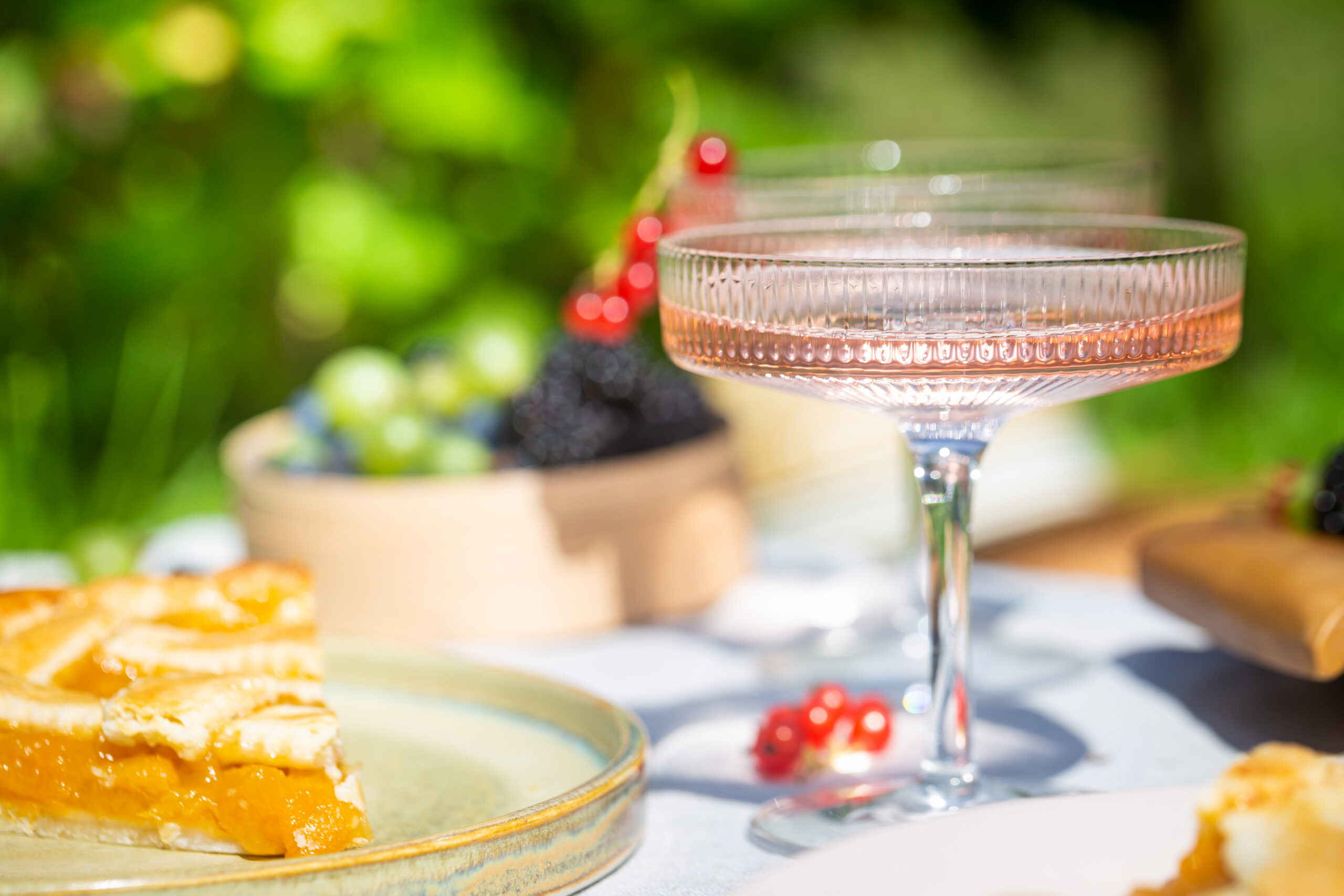 Outdoor summer picnic Outdoor summer lifestyle with a gourmet picnic laid out in a garden with berries, pie and pink drink in stylish glasses. Image by Freepik.